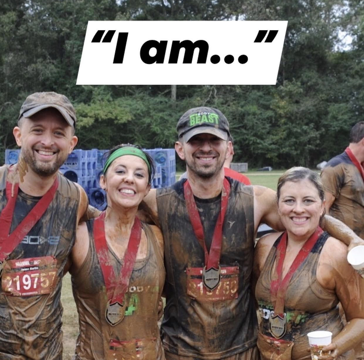 Two men and two women wearing medals and covered in mud from obstacle course Warrior Dash